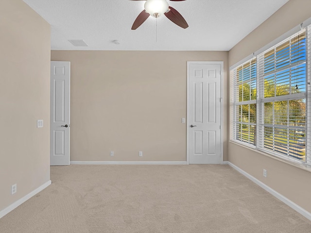 carpeted empty room with a wealth of natural light and ceiling fan