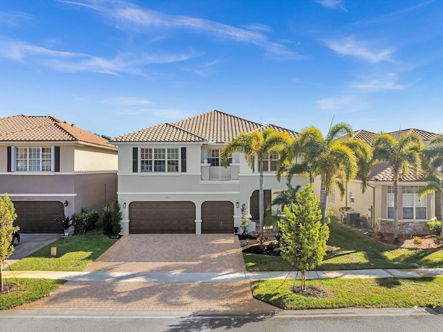 mediterranean / spanish-style home featuring a balcony, a garage, a front lawn, and cooling unit