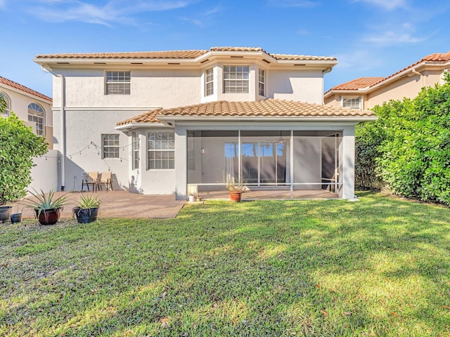 rear view of property with a lawn, a patio area, and a sunroom