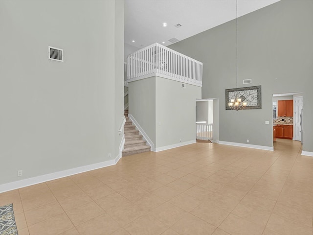 unfurnished living room with light tile patterned flooring, a towering ceiling, and an inviting chandelier