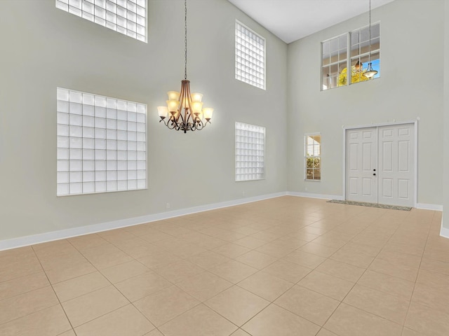 tiled empty room with a towering ceiling, a wealth of natural light, and an inviting chandelier