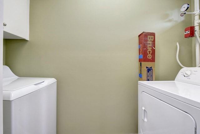 clothes washing area featuring cabinets and separate washer and dryer