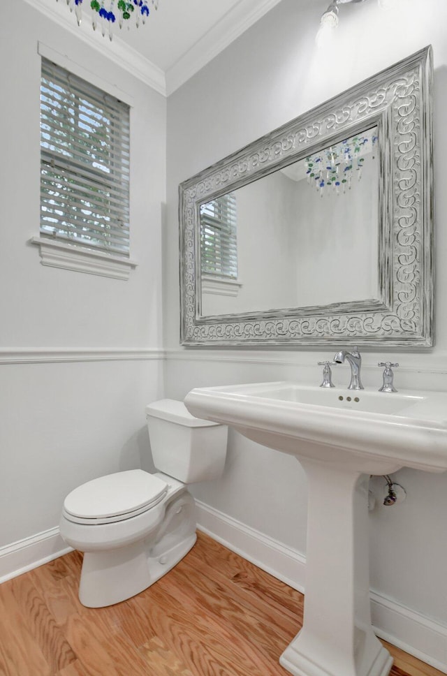 bathroom with a wealth of natural light, crown molding, wood-type flooring, and toilet