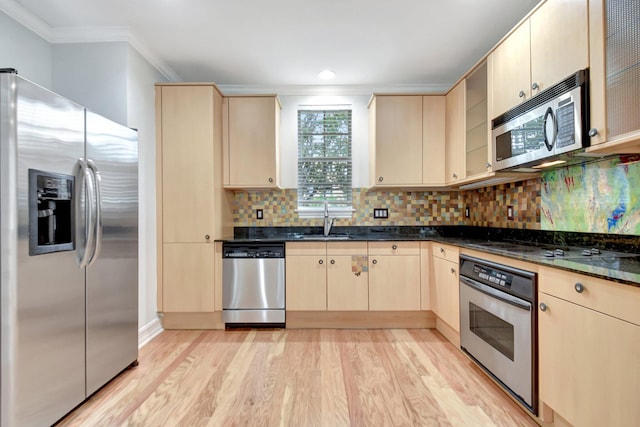 kitchen with sink, light brown cabinets, light hardwood / wood-style flooring, dark stone counters, and appliances with stainless steel finishes