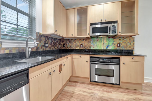 kitchen featuring sink, stainless steel appliances, dark stone counters, light brown cabinetry, and light wood-type flooring