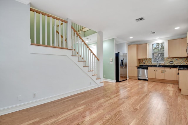 kitchen featuring backsplash, light wood-type flooring, ornamental molding, light brown cabinetry, and appliances with stainless steel finishes