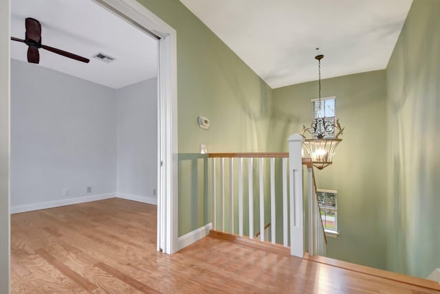 hallway featuring a healthy amount of sunlight, a notable chandelier, and hardwood / wood-style floors