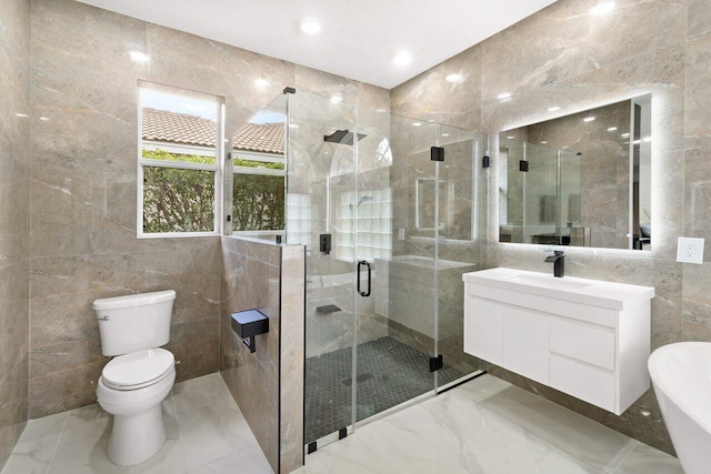 bathroom with vanity, toilet, a shower with door, and tile walls