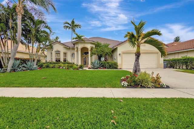 mediterranean / spanish-style home with a front yard, stucco siding, concrete driveway, a garage, and a tile roof