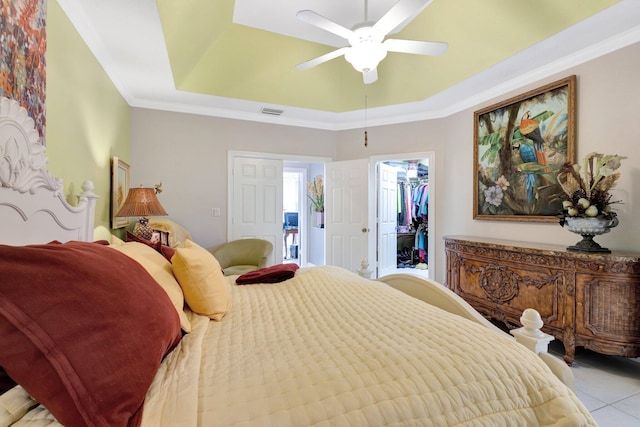 bedroom with visible vents, a walk in closet, crown molding, ceiling fan, and a tray ceiling