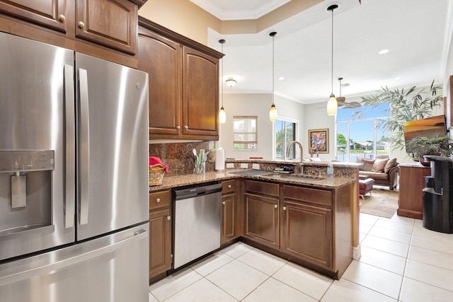 kitchen featuring ornamental molding, a sink, appliances with stainless steel finishes, a peninsula, and stone counters