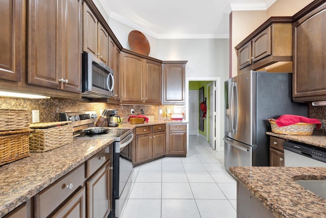 kitchen featuring light tile patterned flooring, backsplash, appliances with stainless steel finishes, and ornamental molding