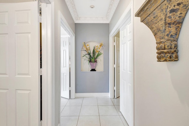 hall featuring light tile patterned floors, baseboards, and ornamental molding