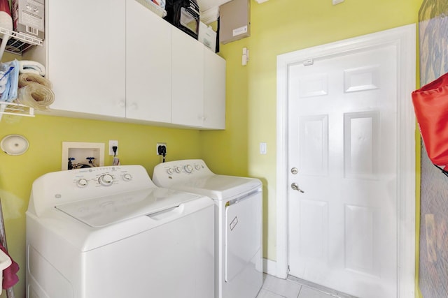 laundry area featuring washing machine and dryer, light tile patterned floors, and cabinet space