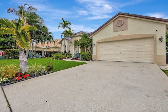 mediterranean / spanish-style house featuring stucco siding, driveway, a garage, and a front lawn