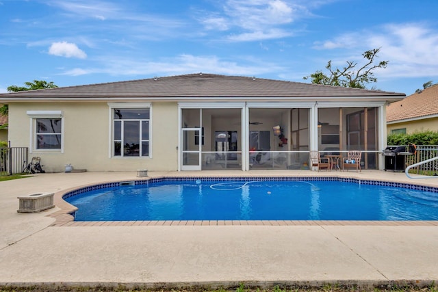 outdoor pool with a patio area, a grill, and a sunroom