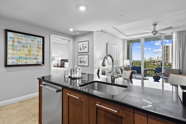 kitchen featuring dark stone counters, sink, stainless steel dishwasher, ceiling fan, and light tile patterned flooring