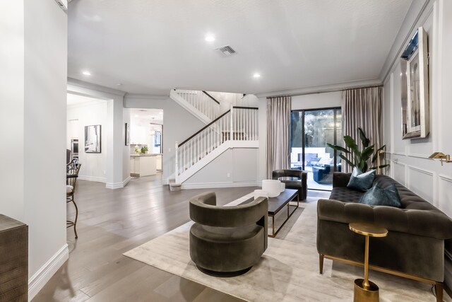 living area featuring stairs, plenty of natural light, wood finished floors, and visible vents