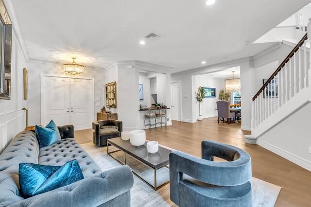 living area with stairway, visible vents, a chandelier, and ornamental molding