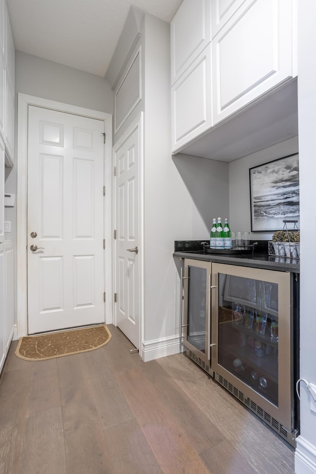 interior space with wine cooler, hardwood / wood-style flooring, and bar area