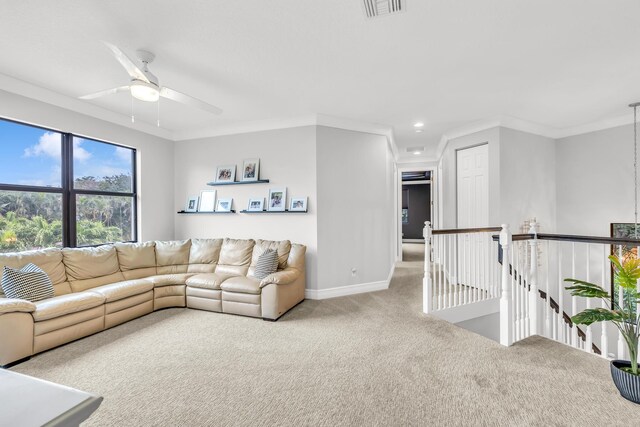 living area featuring light colored carpet, a ceiling fan, baseboards, visible vents, and ornamental molding