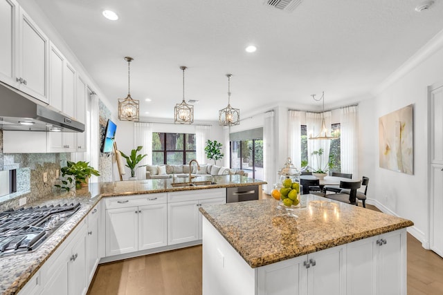 kitchen with sink, white cabinetry, hanging light fixtures, light wood-type flooring, and appliances with stainless steel finishes