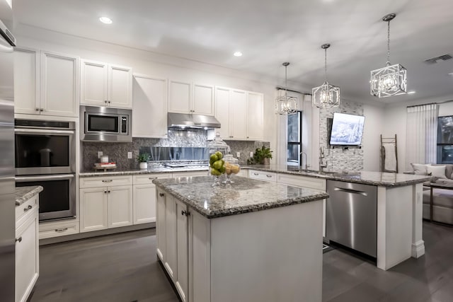 kitchen with appliances with stainless steel finishes, visible vents, a kitchen island, and under cabinet range hood