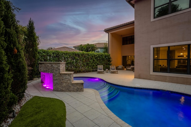 pool at dusk with a patio