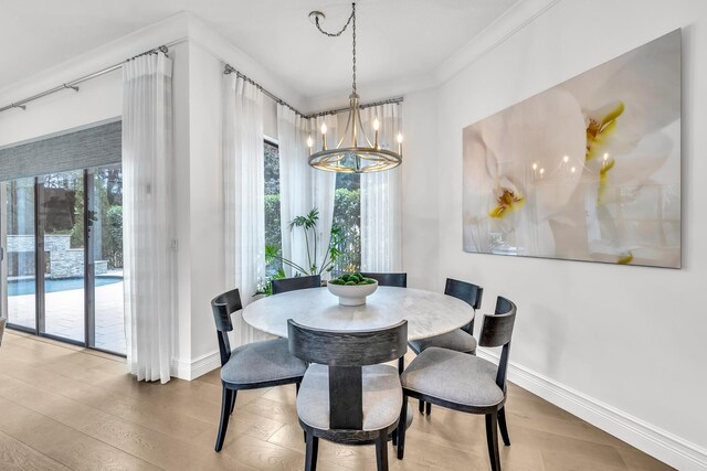 dining room featuring a notable chandelier, plenty of natural light, baseboards, and wood finished floors