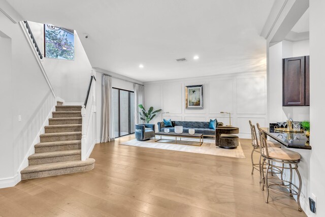 living room with visible vents, wood finished floors, a decorative wall, a notable chandelier, and recessed lighting