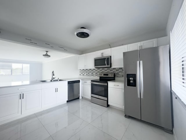 kitchen featuring decorative backsplash, appliances with stainless steel finishes, white cabinetry, and sink