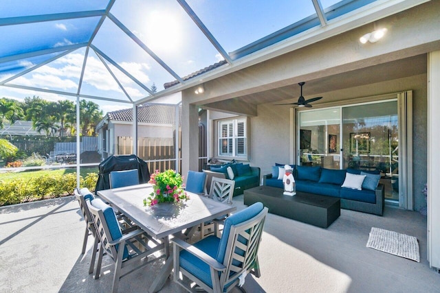 view of patio featuring ceiling fan, glass enclosure, area for grilling, and outdoor lounge area