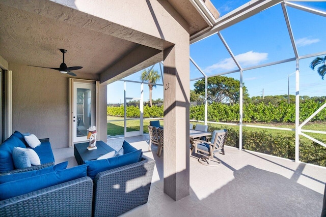 view of patio with an outdoor hangout area, ceiling fan, and glass enclosure