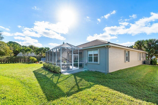 rear view of house with central AC and a yard