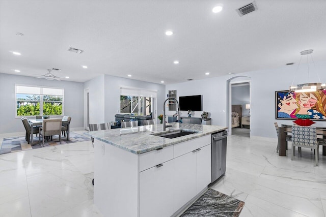 kitchen featuring light stone counters, hanging light fixtures, an island with sink, white cabinetry, and sink