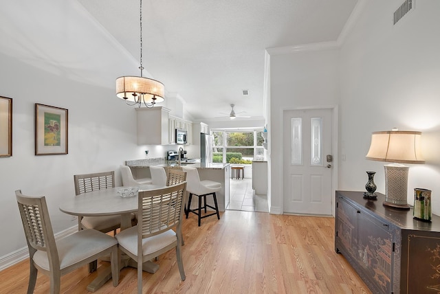 dining room with light hardwood / wood-style floors, vaulted ceiling, crown molding, and ceiling fan with notable chandelier