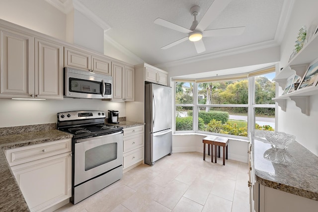 kitchen with appliances with stainless steel finishes, dark stone countertops, and cream cabinetry