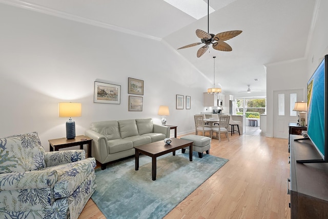 living room featuring ceiling fan, ornamental molding, vaulted ceiling, and light wood-type flooring