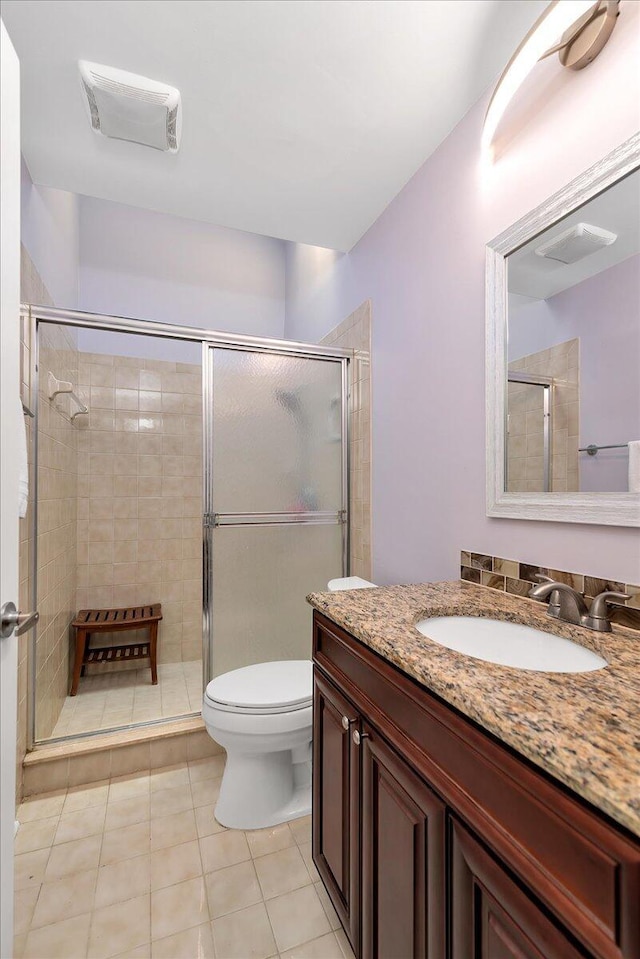 bathroom featuring tile patterned flooring, vanity, toilet, and a shower with door