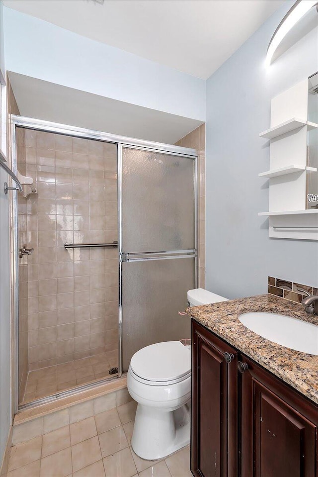 bathroom with tile patterned flooring, vanity, toilet, and an enclosed shower