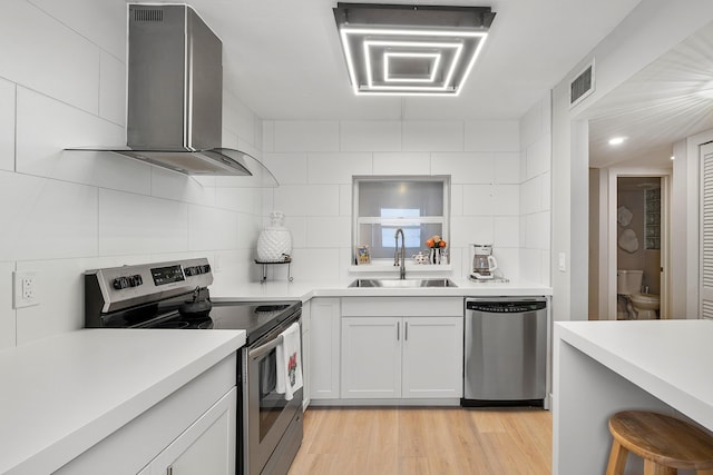 kitchen with wall chimney exhaust hood, stainless steel appliances, decorative backsplash, white cabinets, and sink