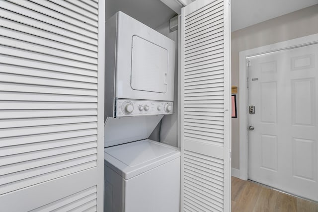 laundry room with stacked washer / drying machine and light wood-type flooring