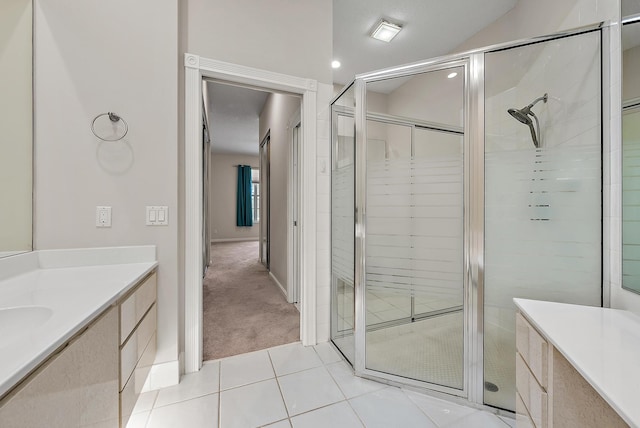 bathroom featuring a shower with shower door, vanity, and tile patterned flooring