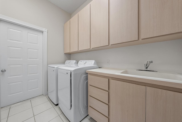 laundry room with cabinets, light tile patterned floors, washer and clothes dryer, and sink