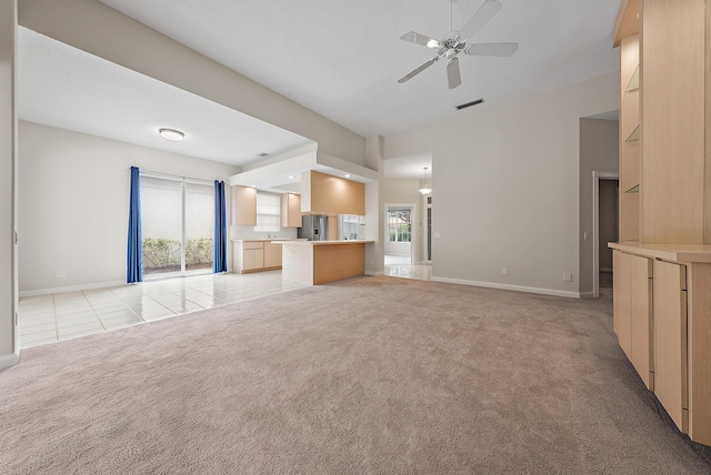 unfurnished living room featuring ceiling fan, a wealth of natural light, and light colored carpet