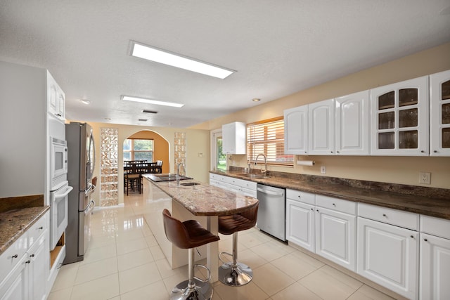 kitchen with white cabinets, dishwasher, light tile patterned flooring, and a kitchen breakfast bar