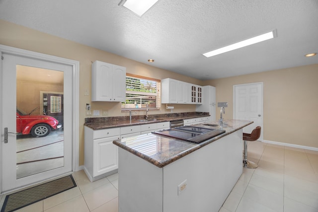 kitchen featuring sink, a kitchen island, a textured ceiling, white cabinets, and appliances with stainless steel finishes