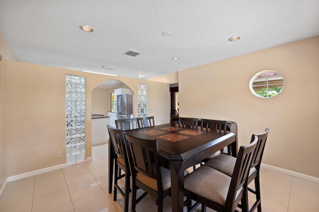 dining space with a textured ceiling and light tile patterned flooring