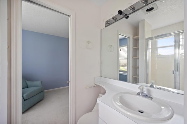 bathroom featuring vanity, a textured ceiling, toilet, and a shower with door