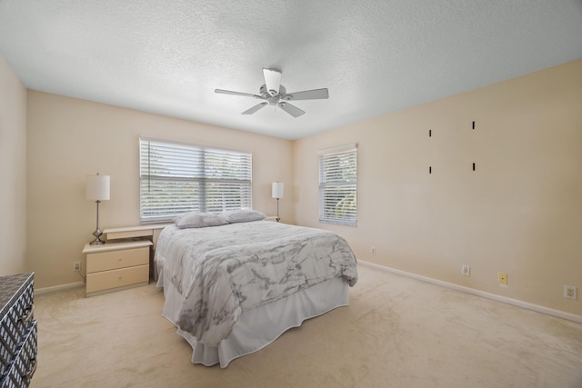 bedroom with ceiling fan, light colored carpet, and a textured ceiling